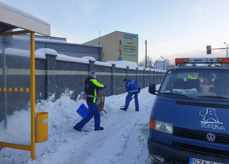 Pracownicy MPWIK rozpalają koksownik, w tle samochod spółki.